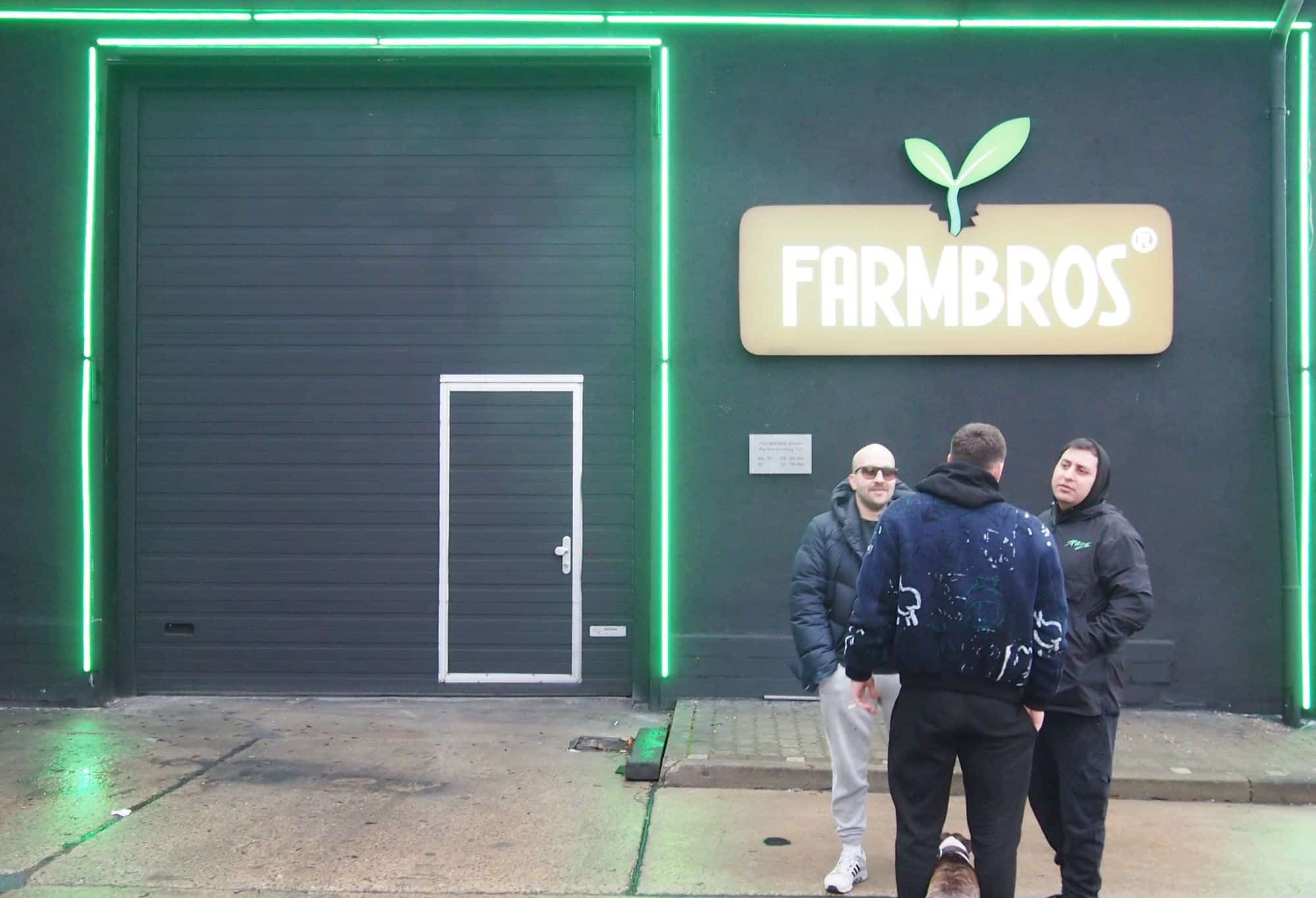 Drei Personen stehen vor einem Gebäude, das mit grünen Neonlichtern eingefasst ist. Rechts ist ein Schild mit der Aufschrift "FARMBROS", das von einem Blattlogo begleitet wird. Die Personen scheinen eine Unterhaltung vor dem Eingang zu führen. Die Szene wirkt geschäftlich und könnte sich um Themen wie Cannabis-Marketing oder CBD-Handel drehen, passend zur Präsenz von 420MKT, einer spezialisierten Marketingagentur. Der Ort könnte ein Lager oder Büro für Cannabisprodukte sein.
